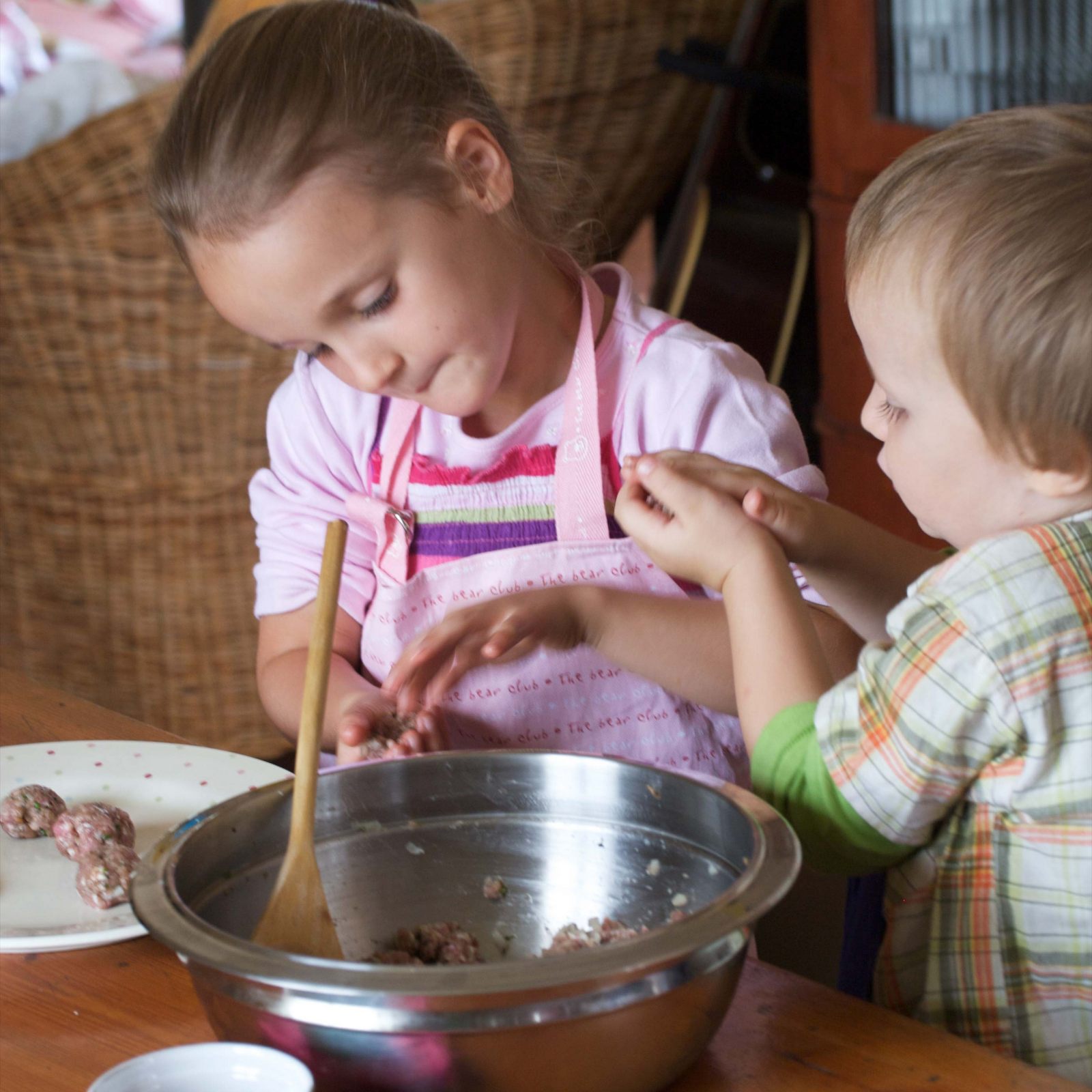 Kids making meatballs with tomato sauce