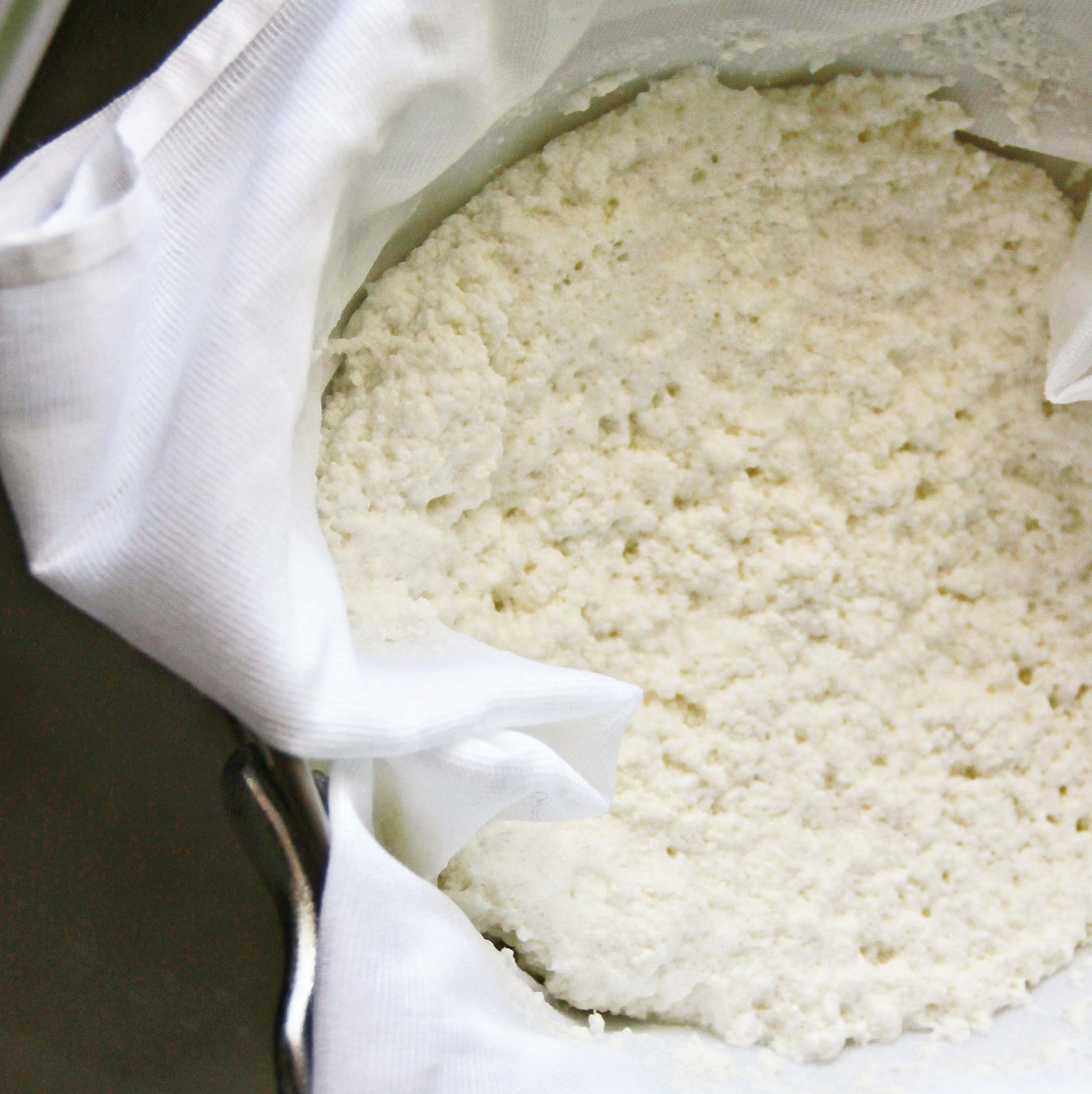 Homemade paneer being drained using cheese cloth.